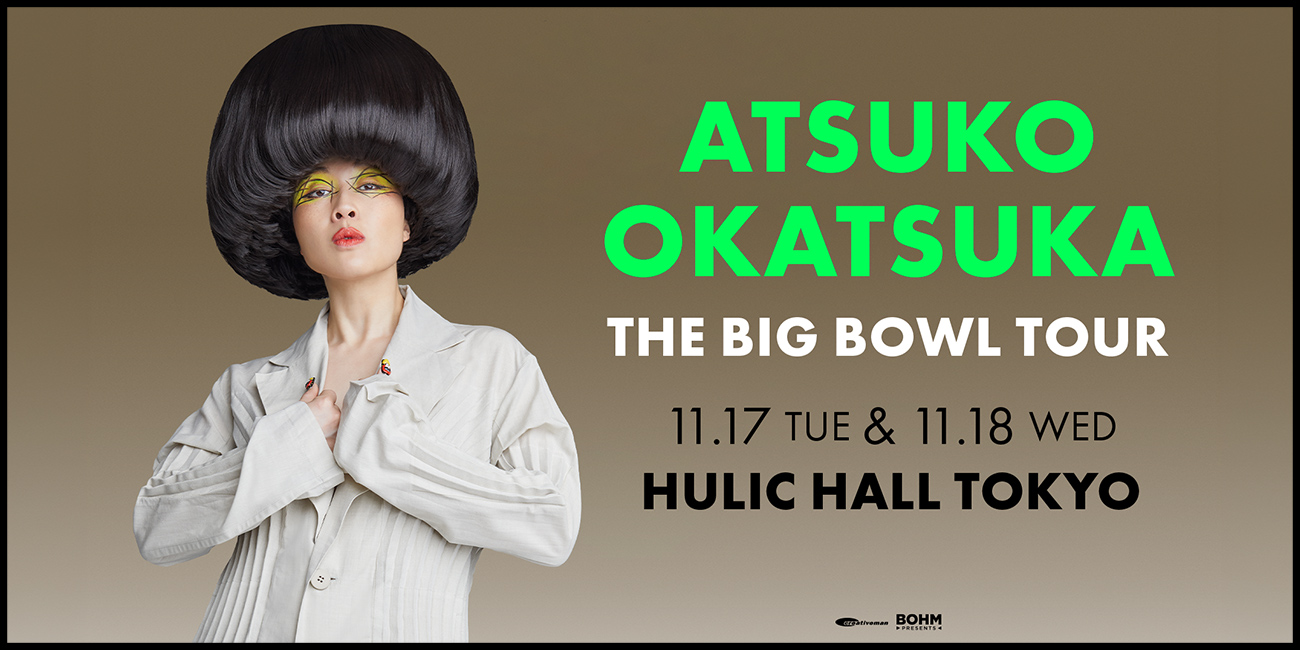 تظهر Atsuko Okatsuka بقصة شعر سوداء مبالغ فيها على شكل وعاء، وملابس بيضاء ويدين متلاصقتين على خلفية رمادية بنية. تذكر الكتابة الخضراء والبيضاء The Big Bowl Tour وHulic Hall Tokyo.
